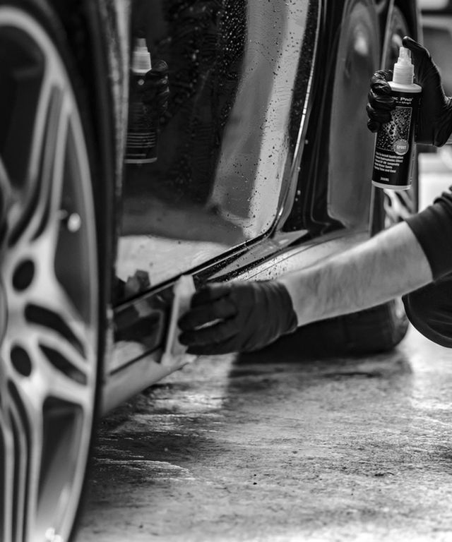 Professional detailer polishing the bodywork of a luxury car by hand
